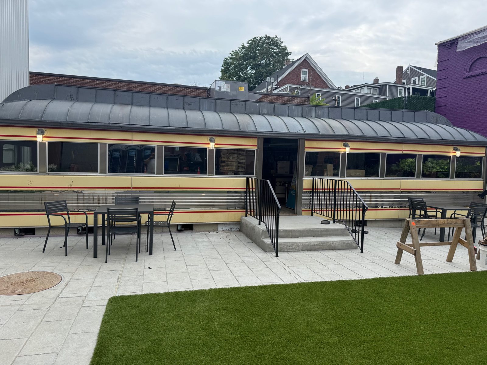Vintage diner car with exterior sconces over a new patio with tables